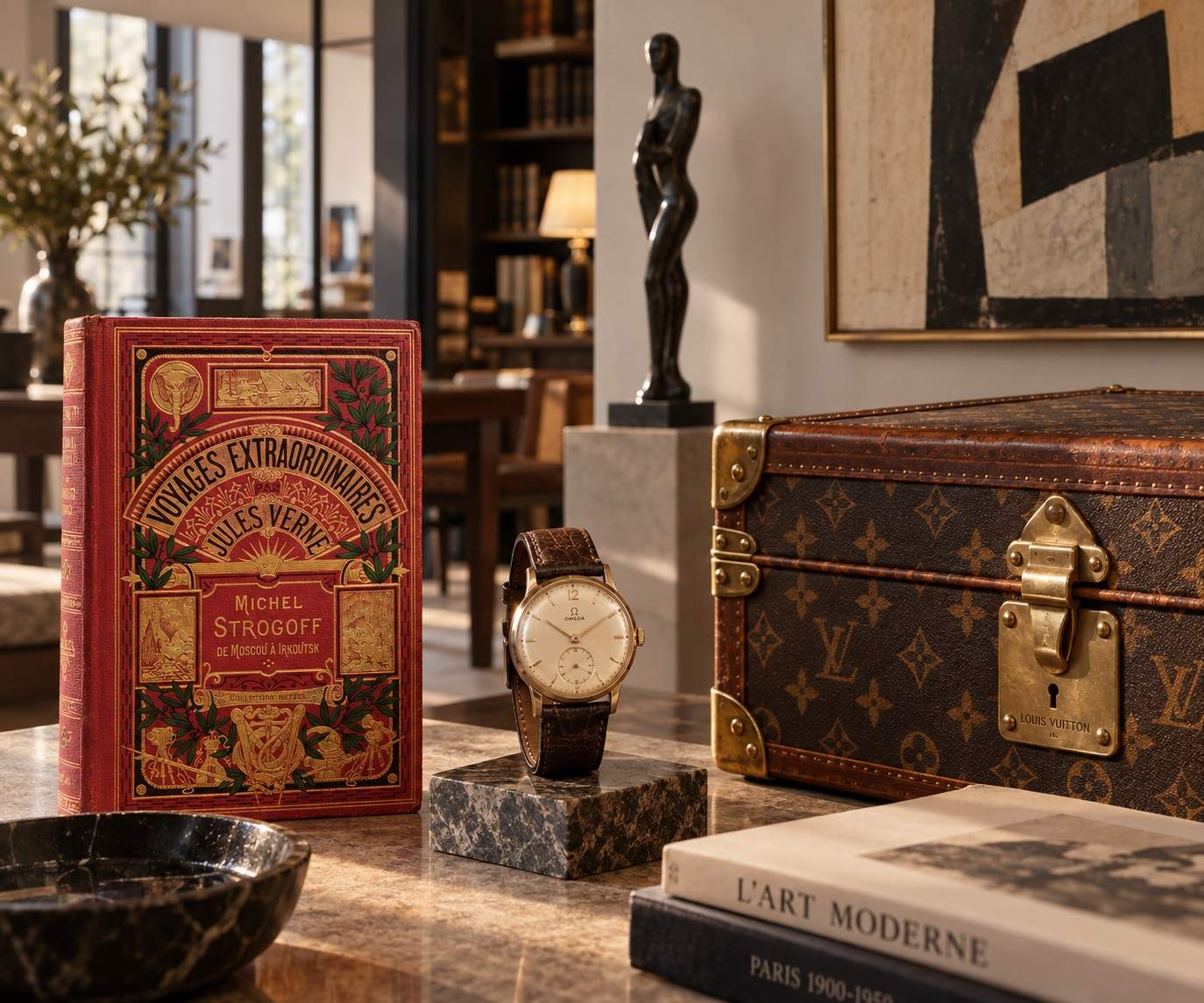 An antique Jules Verne book, a vintage watch and a travel trunk on a marble table